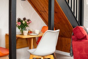 A dining area with a wooden table, white chairs, and a vase of flowers. - Trespaddick - Treworgie Barton Cottages (Cornwall)