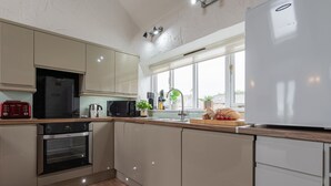A modern kitchen with a built-in oven, microwave, and refrigerator. - Trespaddick - Treworgie Barton Cottages (Cornwall)