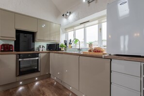 Una cocina moderna con horno empotrado, microondas y refrigerador.