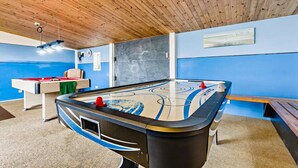 A pool table with a blue and white design, a foosball table, and a billiards table in a room with wooden ceiling and blue walls. - Trespaddick - Treworgie Barton Cottages (Cornwall)