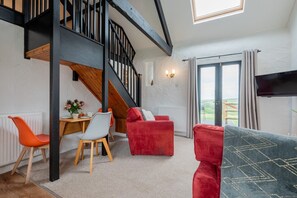 A modern living room with a staircase, a dining area, and a view through a glass door. - Trespaddick - Treworgie Barton Cottages (Cornwall)