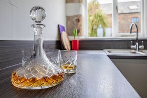 A kitchen counter with a decanter and two glasses of whiskey.