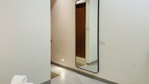 Un pasillo con un espejo grande en la pared, una puerta blanca y una alfombra pequeña en el suelo.