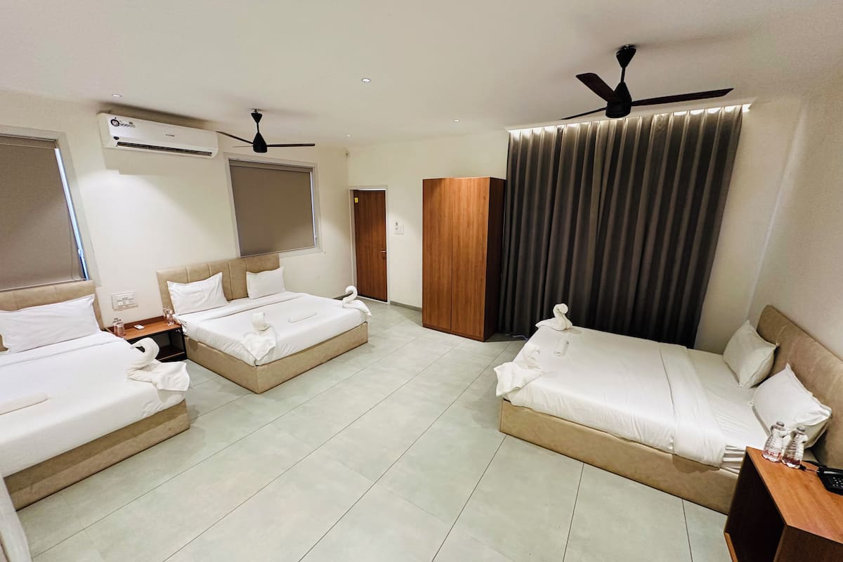 A hotel room with two beds, a wardrobe, a ceiling fan, and a window with curtains.