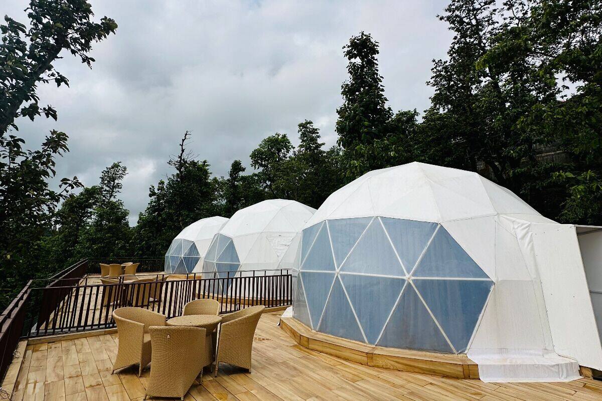 A rooftop terrace with white geodesic domes, wicker furniture, and a wooden deck.