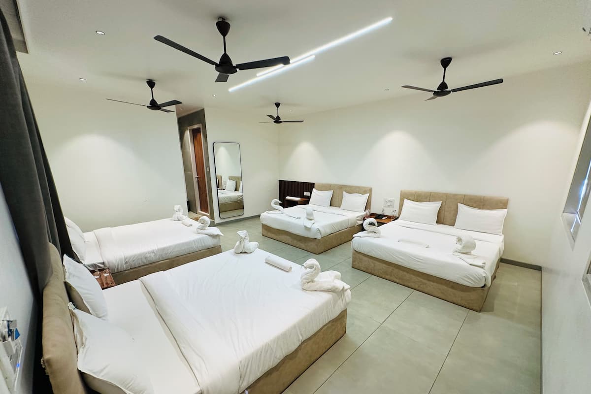 A hotel room with three beds, ceiling fans, and a large mirror.