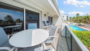 En balkon med swimmingpool, udendørs møbler og udsigt over poolområdet.
