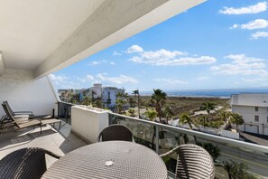 Enjoy the ocean view from this balcony with wicker chairs and a table.