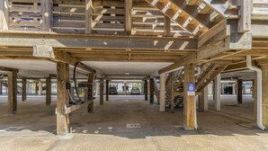 A covered parking area with multiple levels of wooden beams and columns. - Gulf View 17 (Gulf Shores)