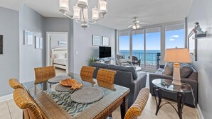 Un salon moderne comprenant un coin repas, un canapé, un téléviseur et un balcon avec vue sur la mer.