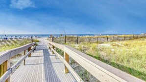 Une promenade en bois qui mène à une plage, avec un ciel dégagé.