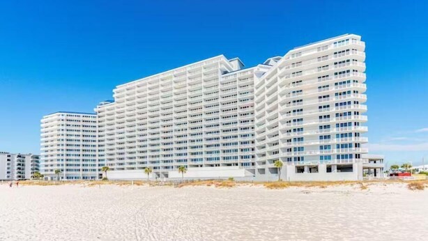 Un hôtel à plusieurs étages au design moderne, doté de balcons et offrant une vue sur la plage.