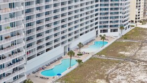Un hôtel de grande hauteur doté de nombreux balcons, d’un espace piscine et d’un accès à la plage.