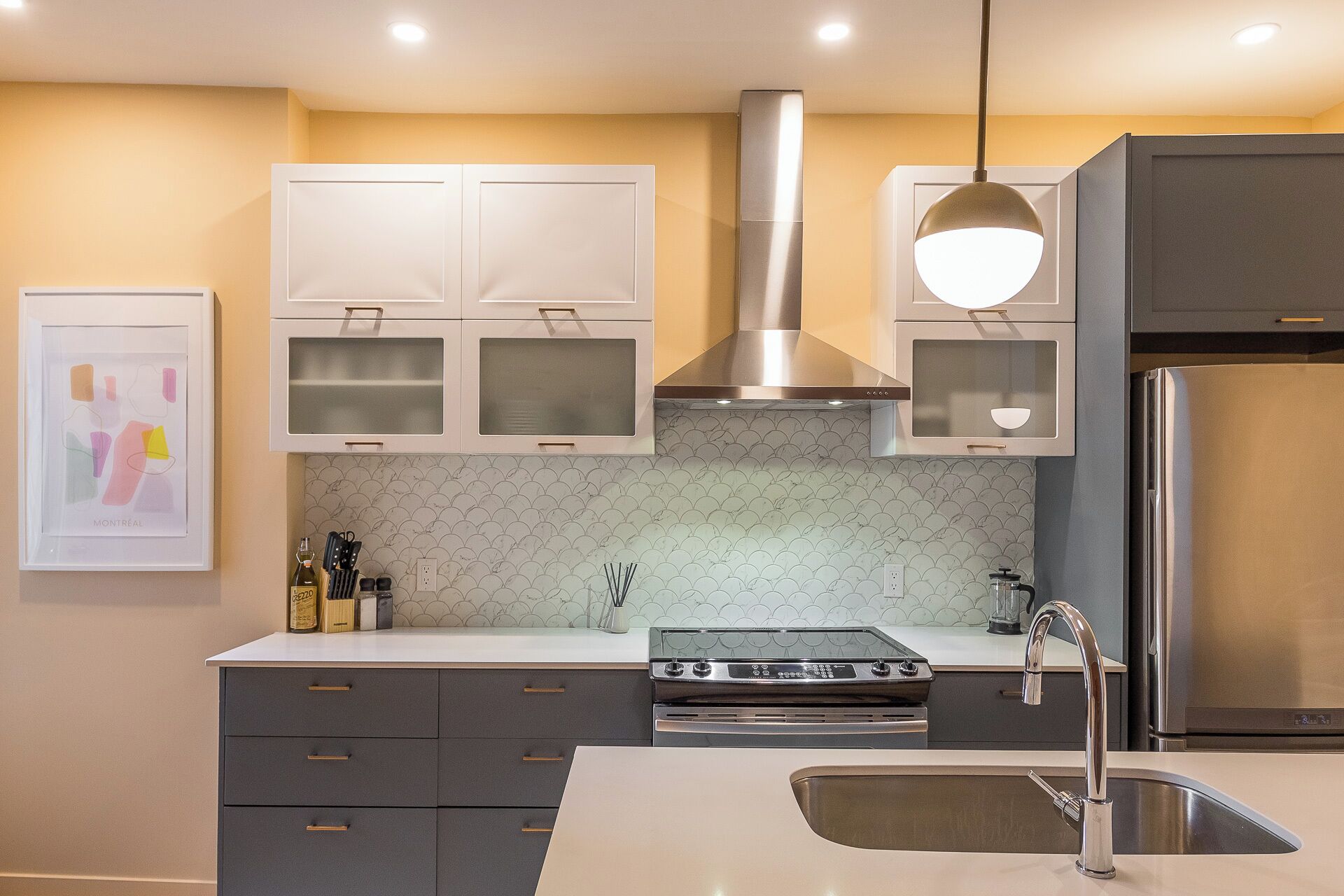 A modern kitchen with white cabinets, a stainless steel range hood, a gas stove, and a built-in oven.
