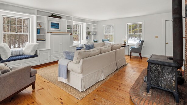 A cozy living room with a sofa, a chair, a fireplace, and built-in shelving. - Green Mountain Getaway (Waitsfield)