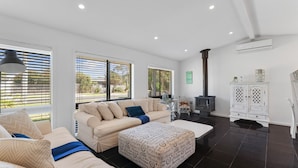 A modern living room with a sofa, ottoman, and a fireplace. - Spacial Rend in Cape Woolamai (Cape Woolamai)