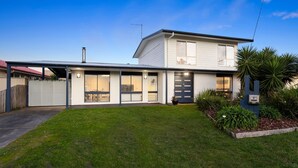 A two-story house with a covered garage, large windows, and a well-maintained lawn. - Spacial Rend in Cape Woolamai (Cape Woolamai)