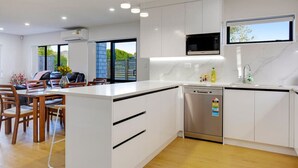 Una cocina moderna con armarios blancos, lavavajillas integrado y una isla grande con fregadero.
