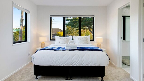 Un dormitorio con una cama grande, dos mesitas de noche y vistas al verdor exterior.