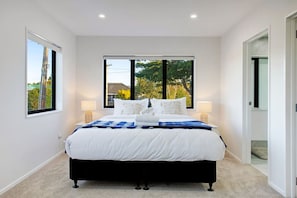 Une chambre avec un grand lit, deux tables de chevet et une vue sur la verdure.