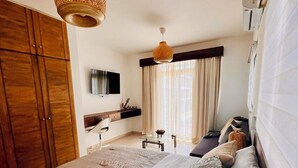 Un dormitorio con una cama grande, armario de madera, televisión y ventana con cortinas.