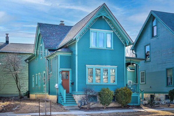 A two-story house with a steep gabled roof, a front porch, and a small front yard.