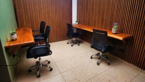 A conference room with a wooden table and four black office chairs. - Ceiba Eco Hostel (La Fortuna)