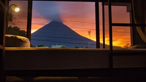 A bed with a view of a mountain at sunset. - Ceiba Eco Hostel (La Fortuna)
