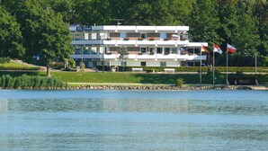 Een hotel met meerdere verdiepingen, balkons, een zwembad en vlaggen.