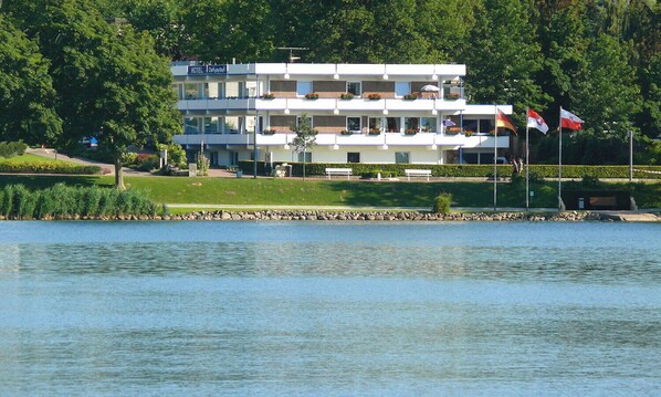 A multi-story hotel with balconies, a swimming pool, and flags.