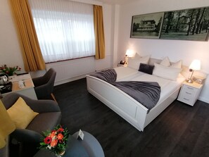 A modern hotel room with a large bed, bedside tables, a desk, and a chair.