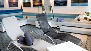 Een moderne binnenzwembadruimte met lounge fauteuils, een klein zwembad en kunstwerken aan de muren.