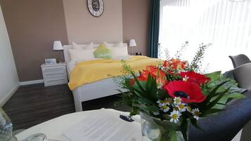 Een hotelkamer met een bed, nachtkastje, lamp en een bloemenarrangement op de tafel.
