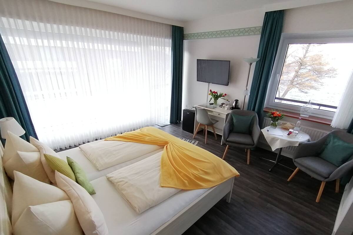 Une chambre d’hôtel avec un lit, un bureau, une chaise, une télévision et une fenêtre avec des rideaux.