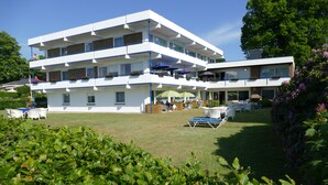 Een hotel met meerdere verdiepingen, terras en een verzorgd gazon.