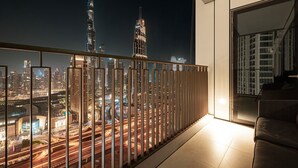 Un balcone con vista sulla città illuminata di notte, con grattacieli illuminati e un'autostrada trafficata.