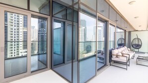 Un intérieur moderne avec de grandes fenêtres du sol au plafond, un balcon avec des sièges et une vue sur la ville.