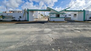 A building with a green and white color scheme, a parking lot, and a clear sky. - Elegant 2-bedroom villa oasis in Punta Cana with WiFi and AC (Punta Cana)