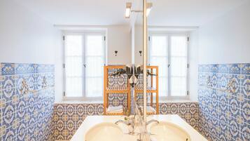 A bathroom with two sinks, a mirror, and a shelf with toiletries.