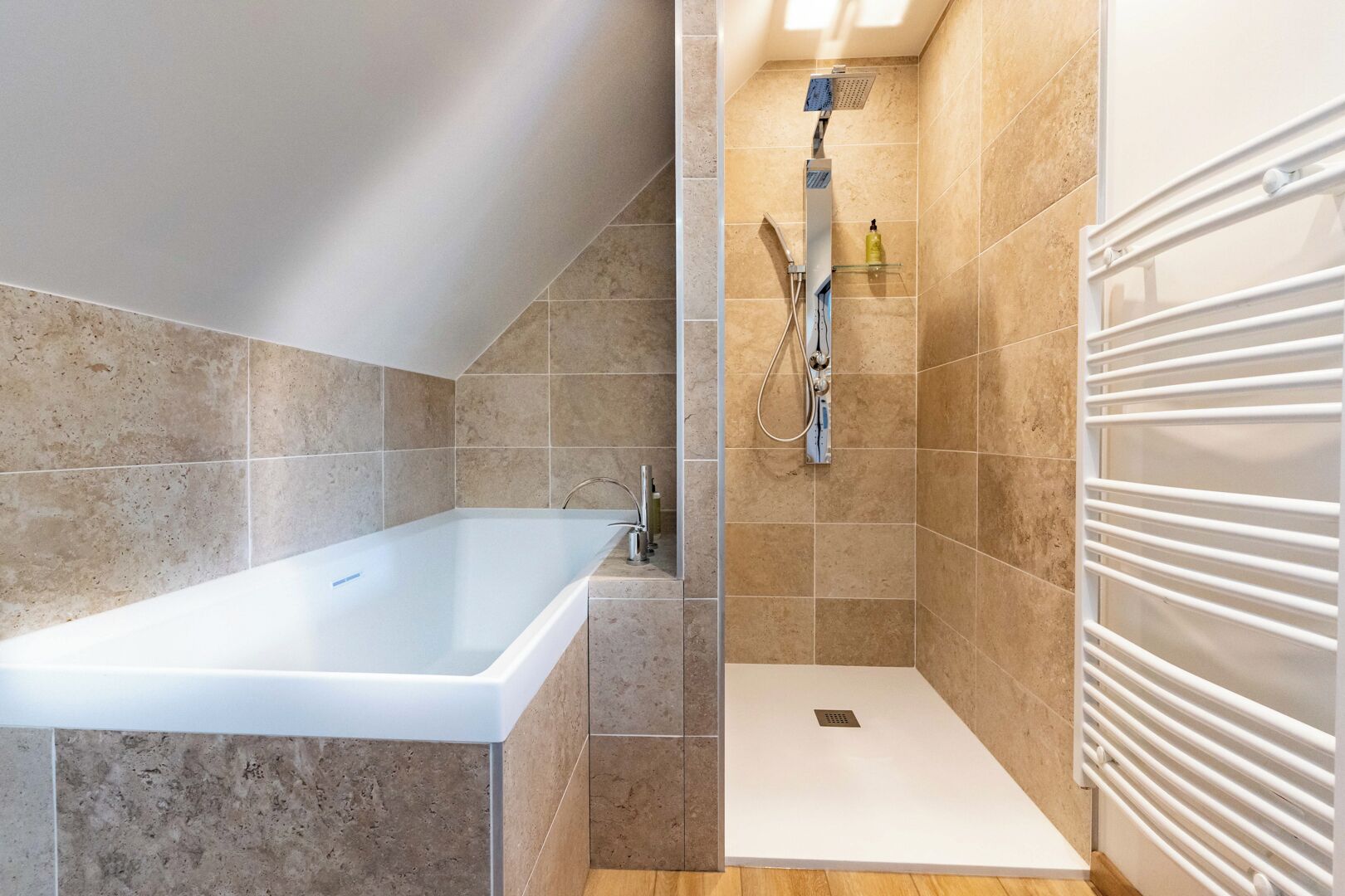 Une salle de bain moderne avec une baignoire, une douche et un radiateur blanc.