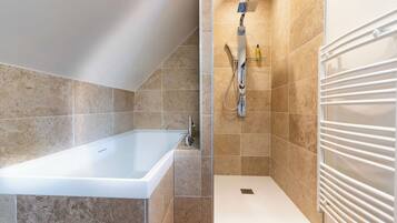 Une salle de bain moderne avec une baignoire, une douche et un radiateur blanc.