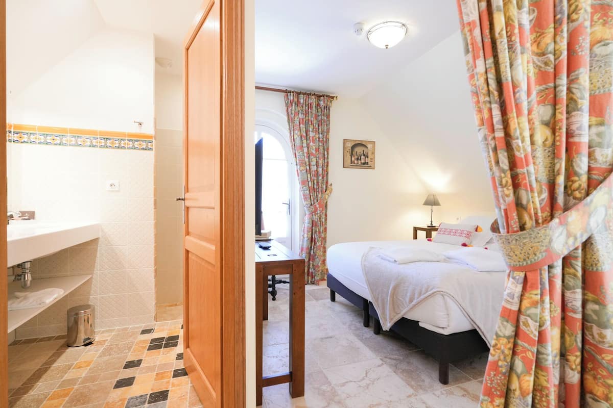 Una camera da letto con un letto, un comodino, una lampada e una finestra con tende.