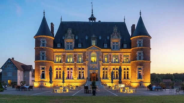 Un grand bâtiment historique à la façade symétrique, doté de nombreuses tours et d’une entrée centrale.