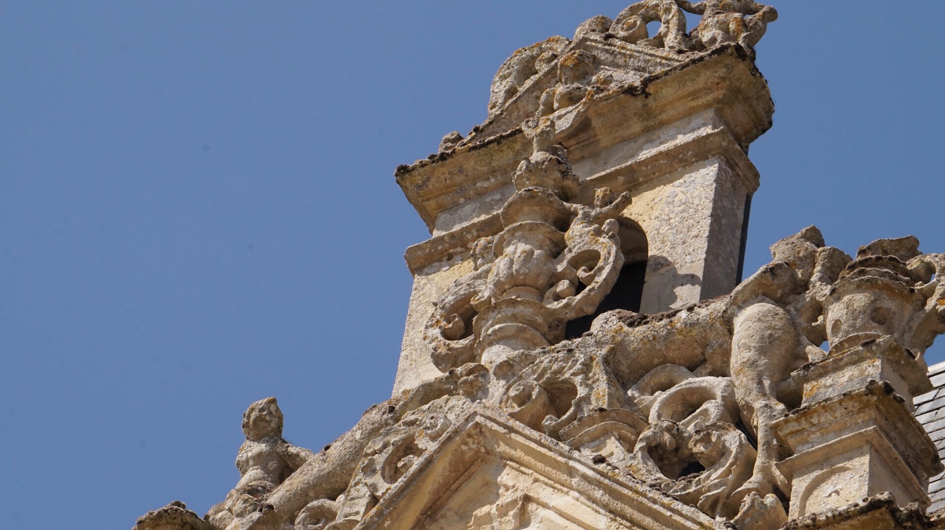 Une façade en pierre richement décorée, ornée de sculptures et de motifs complexes, qui fait probablement partie d’un bâtiment historique.