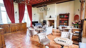 Un salon spacieux avec une cheminée, une table d’échecs et une bibliothèque.