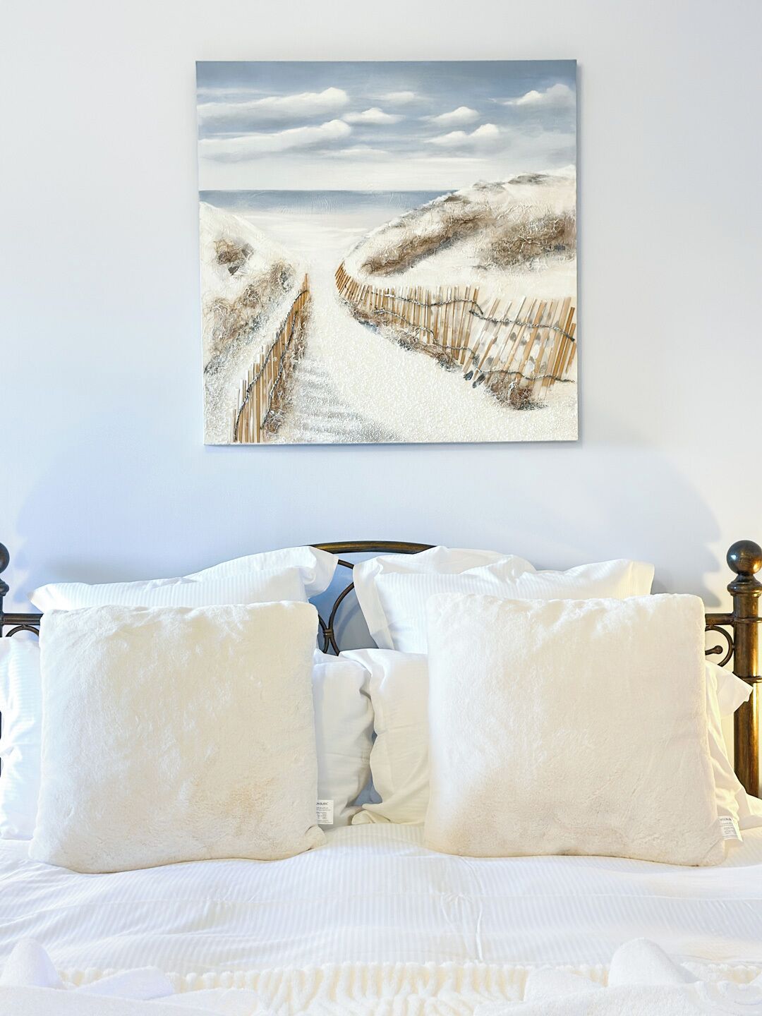 Un dormitorio con cama, ropa de cama blanca y un cuadro de un paisaje nevado en la pared.