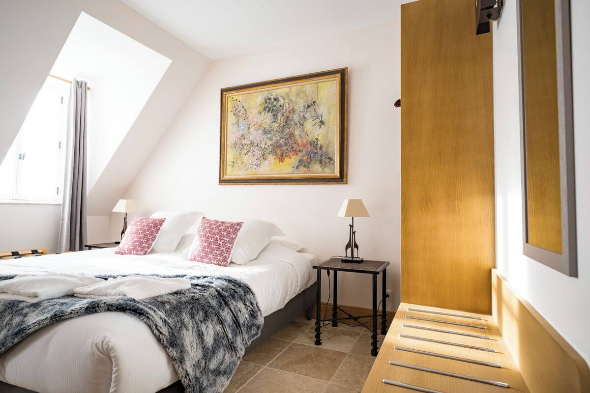 Una camera da letto con un letto, due comodini, un quadro e una porta in legno.