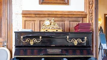 Un piano de cola en una habitación con pared de ladrillo, una obra de arte enmarcada y una puerta de madera.