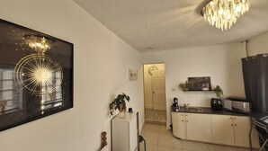 Eine moderne Küche mit Mikrowelle, Spüle und Schränken. Über der Küchenarbeitsfläche hängt eine Chandelier, und an der Wand befindet sich ein großes gerahmtes Kunstwerk.
