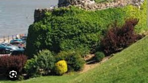 Eine Küstenarchitektur aus Stein mit einem grasbewachsen Vordergrund und Blick auf das Meer.